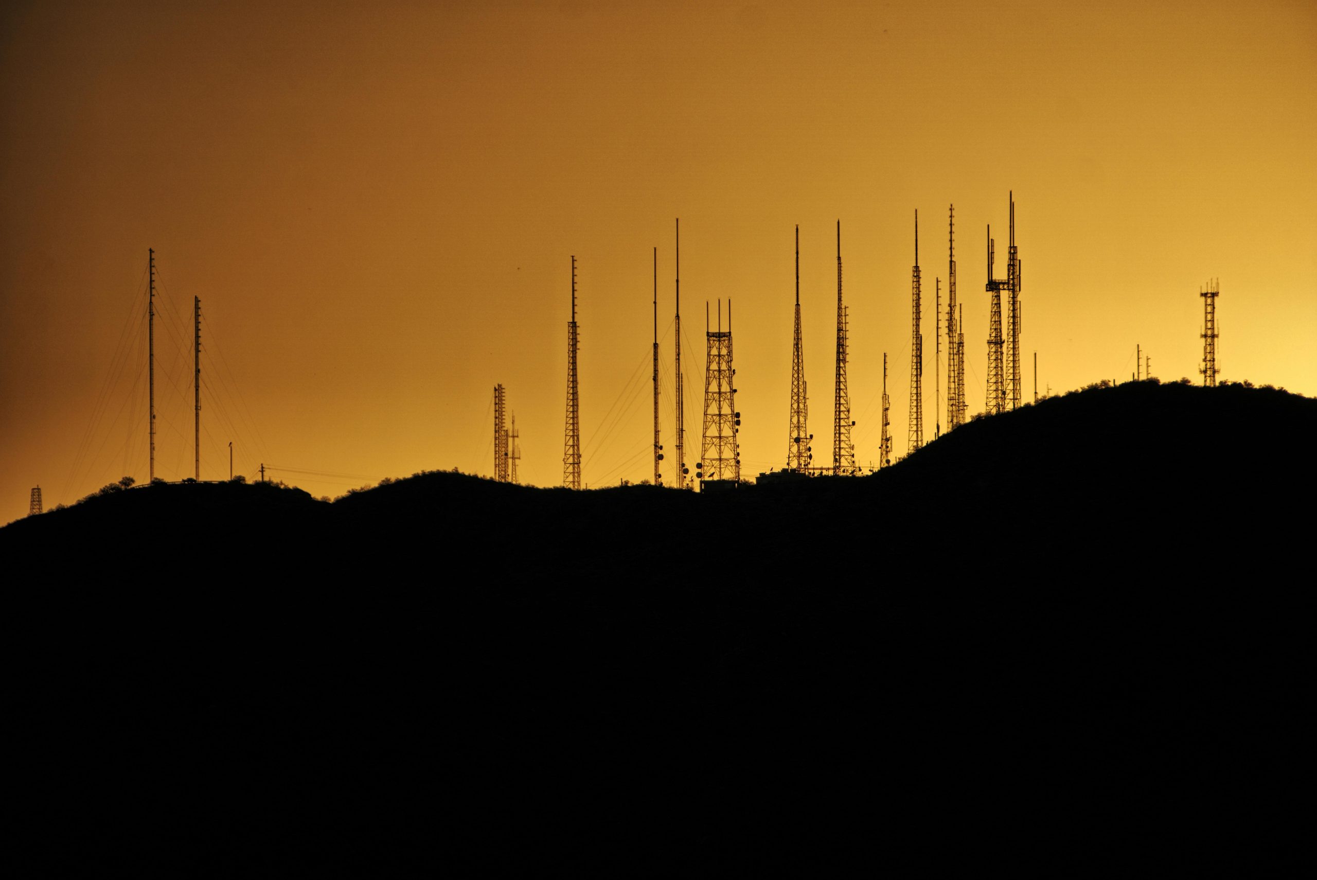 Silhouette of communication towers on a hill at sunset in Phoenix, Arizona.